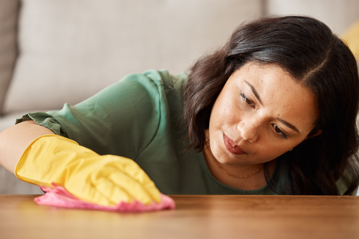 woman polishing a wooden coffee table in living room