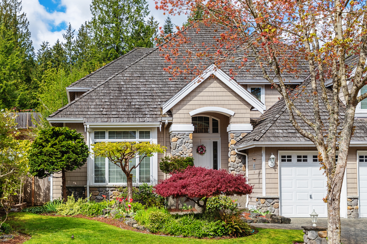 tan-house-with-dwarf-trees-in-front-and-geen-lawn