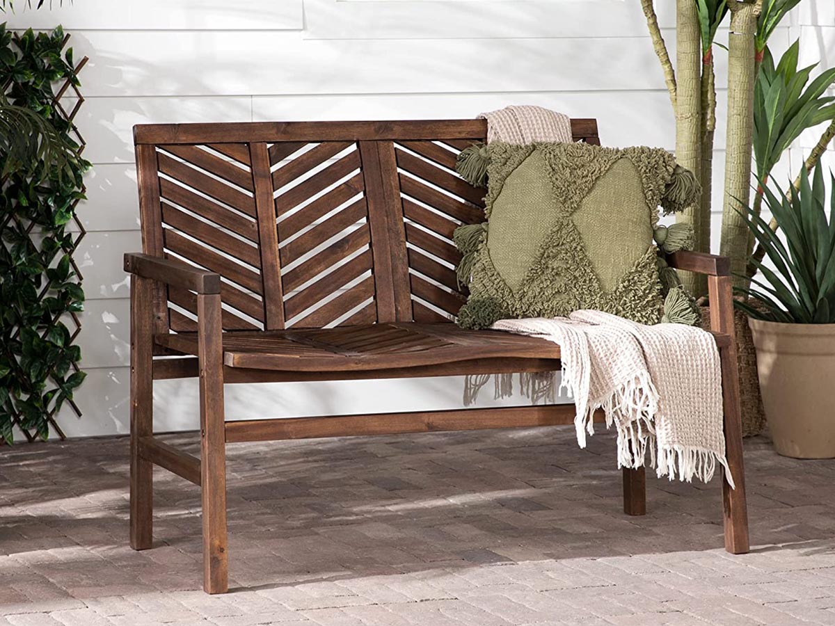 Un banc en bois à l'extérieur sur un patio avec un coussin et une couverture