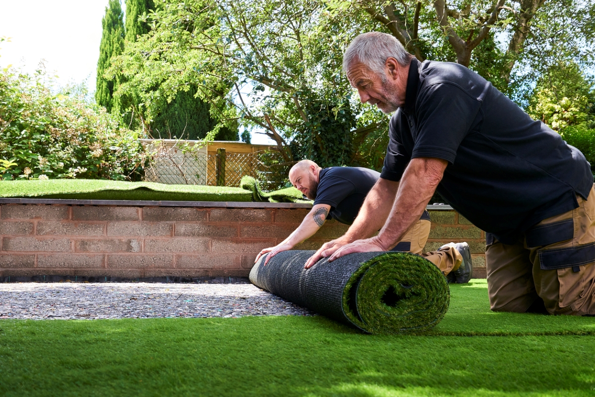 People rolling artificial turf