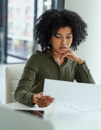 A woman reads a document pensively. 