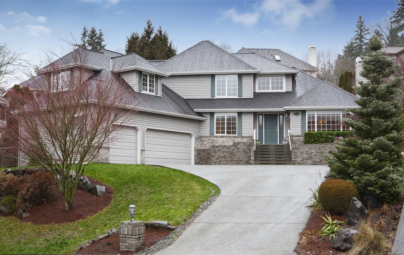 large house with sloped driveway and curved landscaping