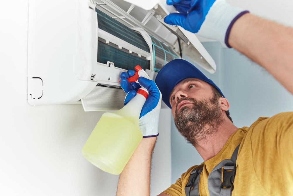 A technician cleans and fixes an indoor AC unit.