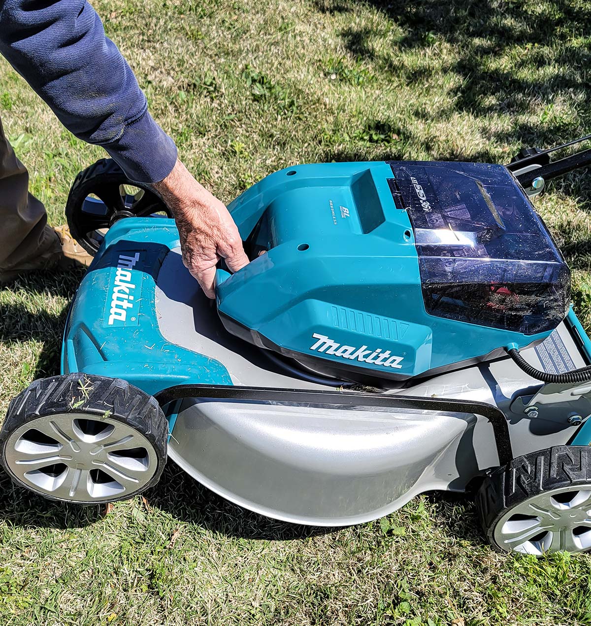 Man lifting Makita lawn mower