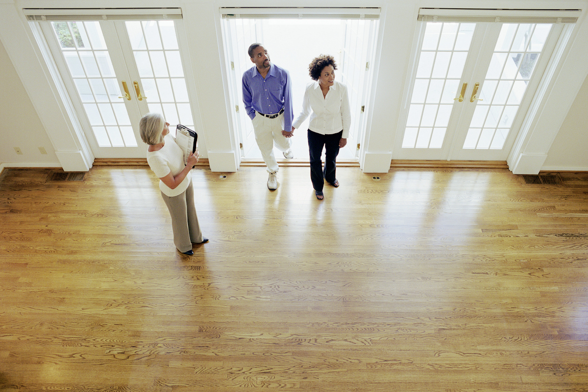 Un agent immobilier montre à un couple une maison à vendre avec du parquet.