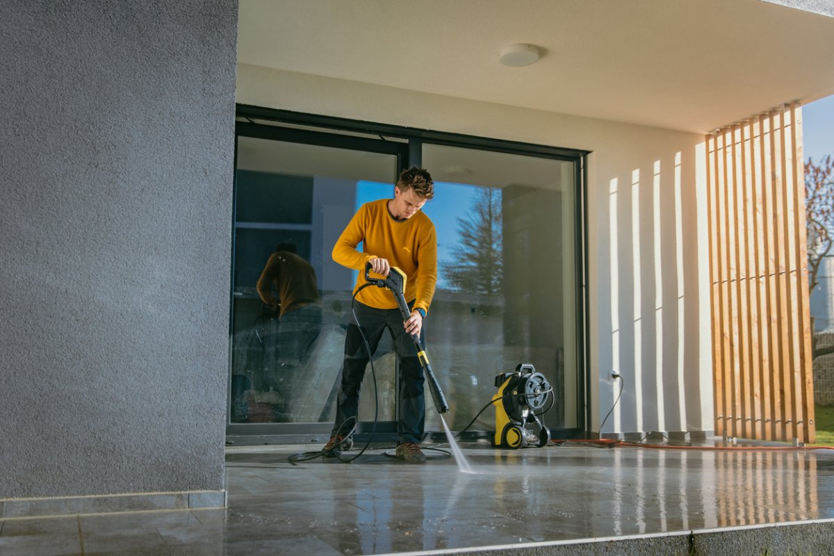 A person pressure-washes a deck. 