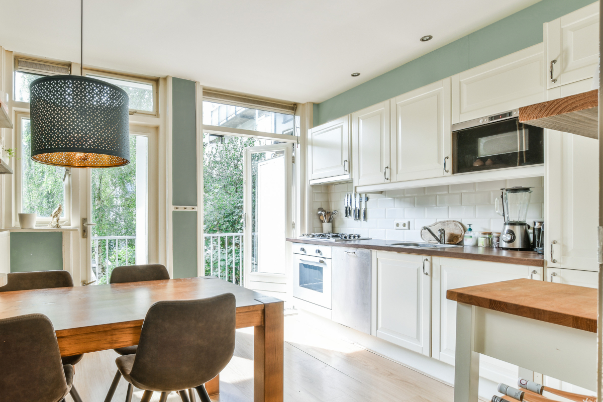 A small kitchen with sage green accent wall paint above the cabinets.