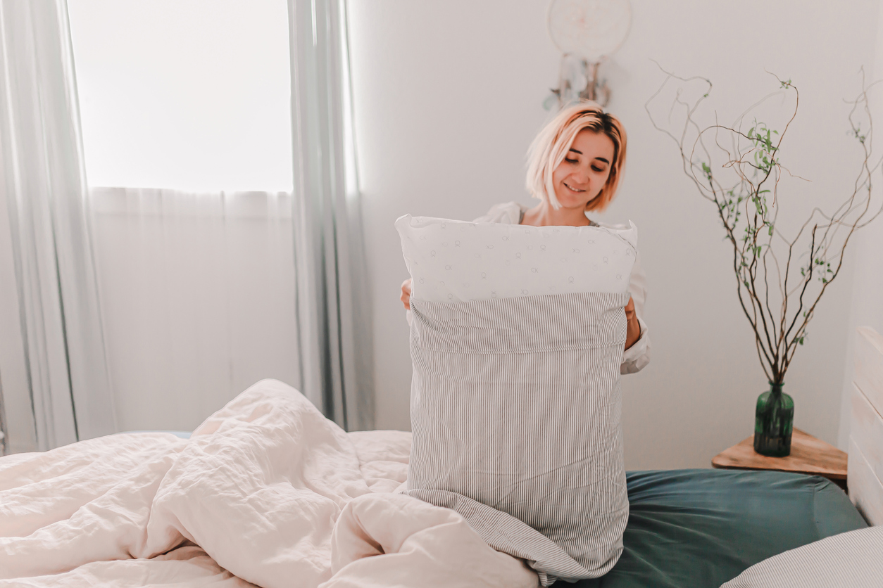 a young woman removes the pillowcase from her pillow