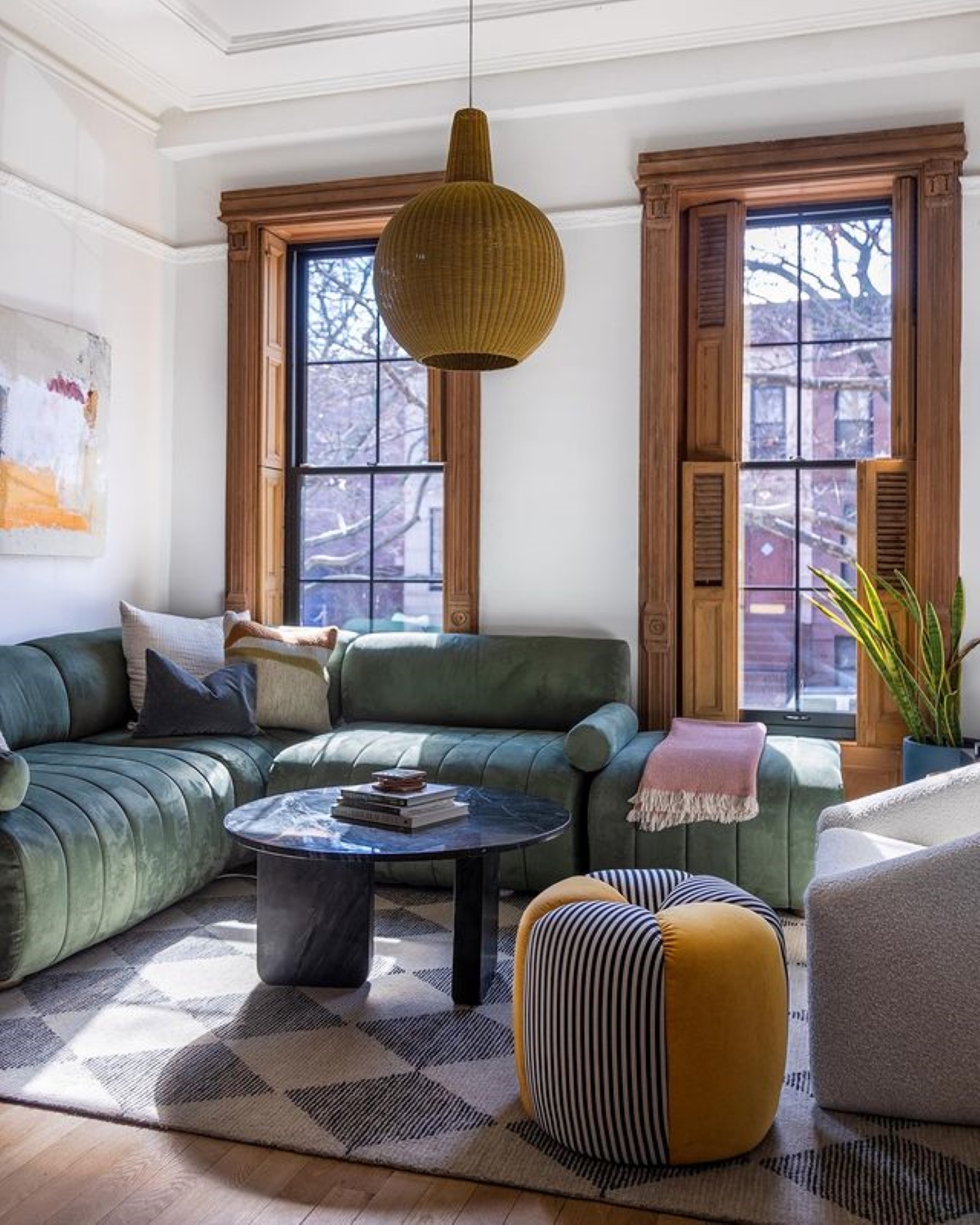 Living room with green velvet couch on patterned rug.