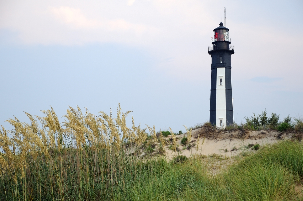 Phare sur un paysage de plage herbeuse.