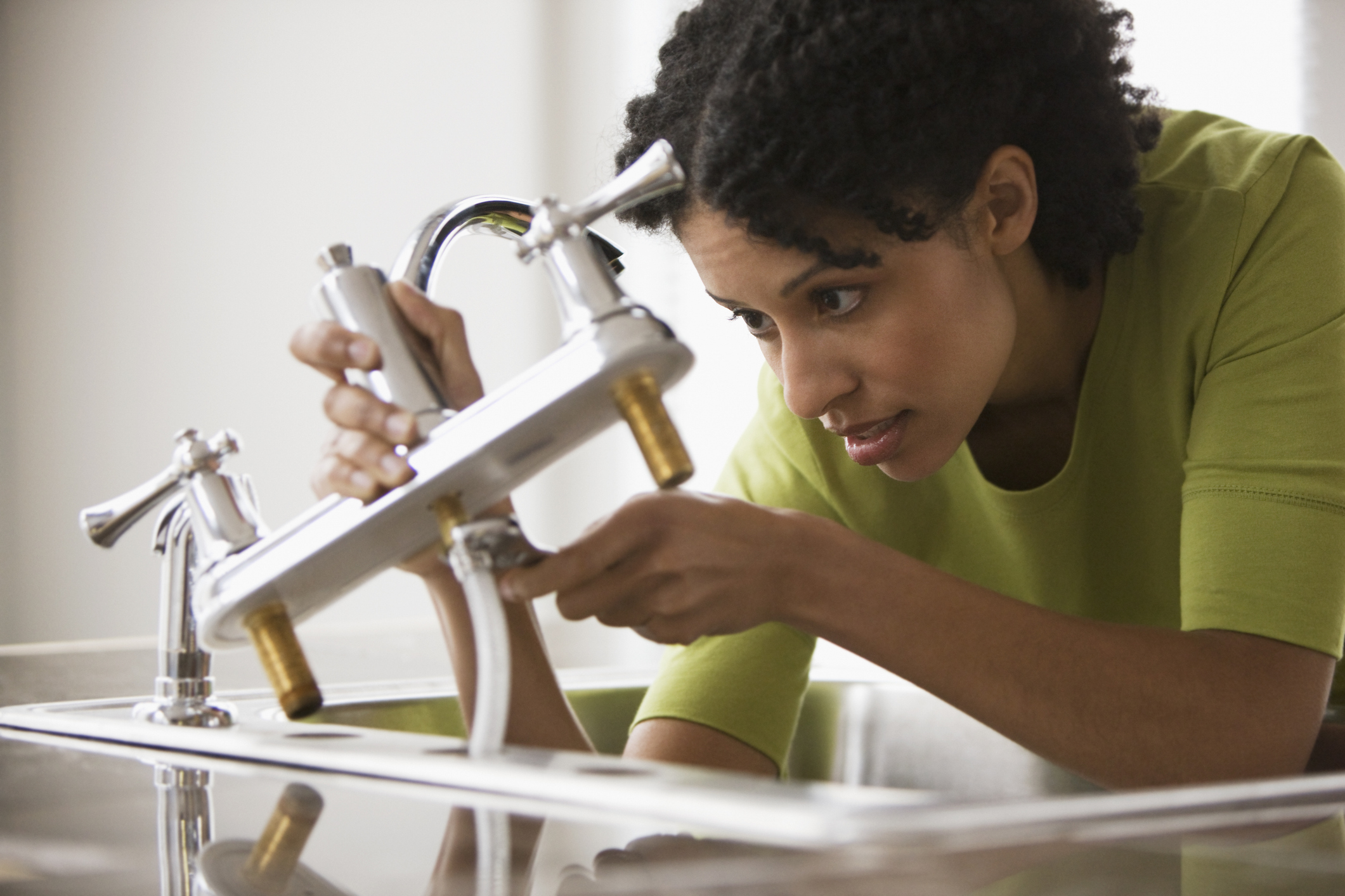 A person installs a new kitchen faucet