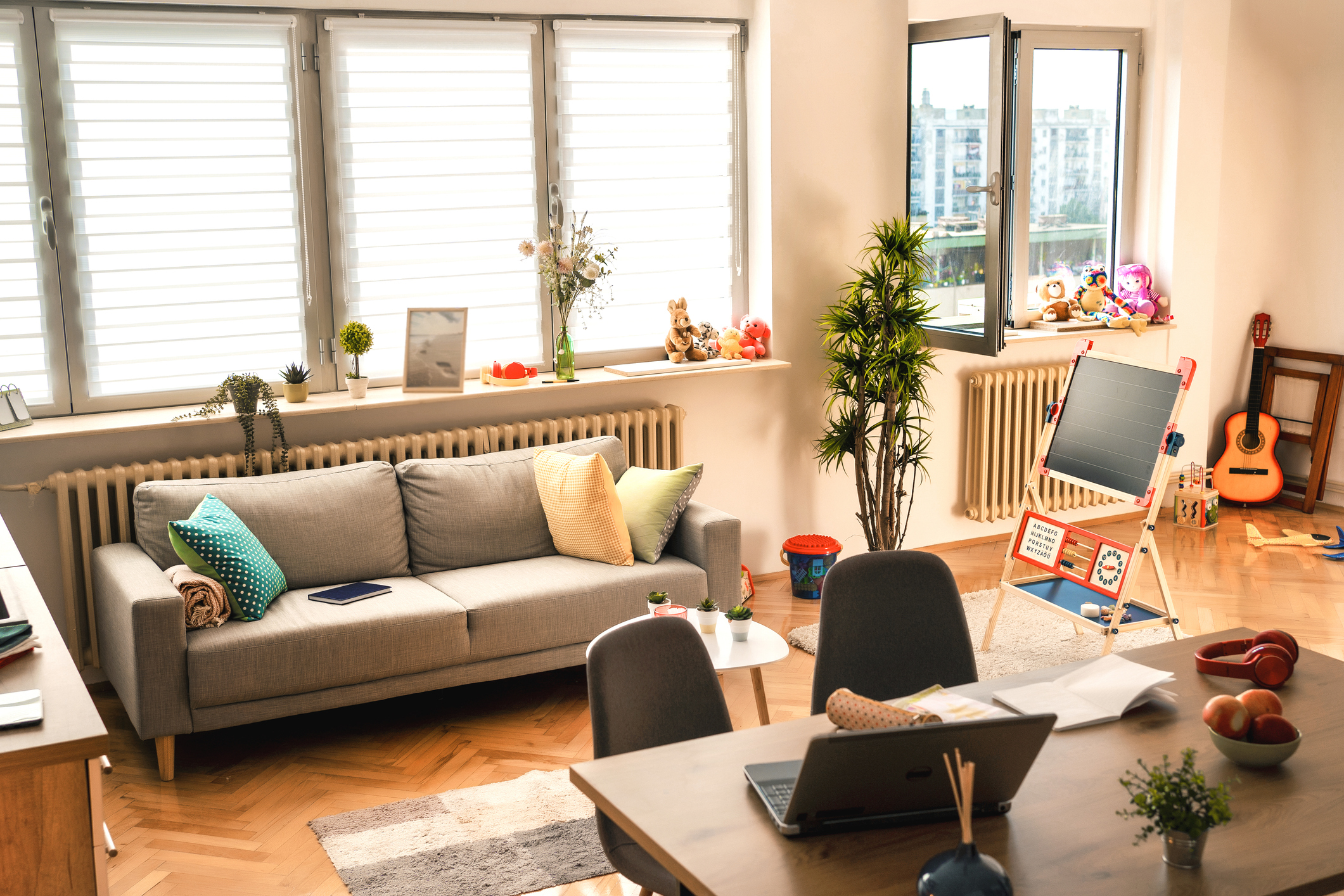 A living room interior with hardwood floors, many windows, and a children's play area off to the side.