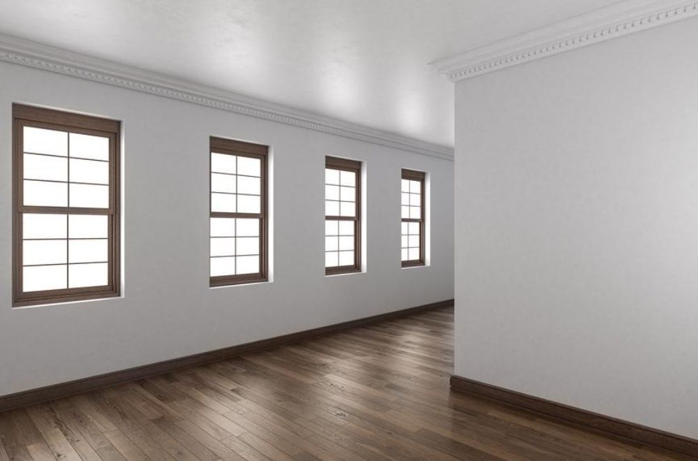 A row of four double-hung windows with brown trim in an airy, white room.