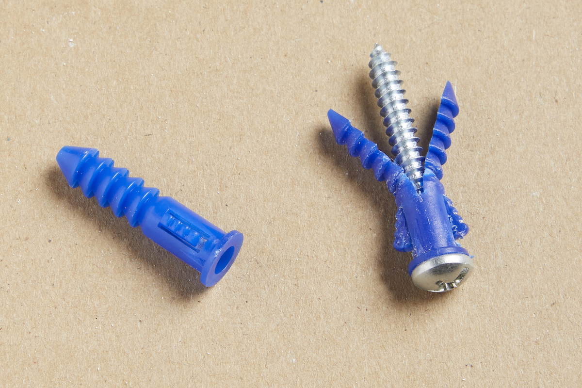 Two expansion drywall anchors against a brown background.