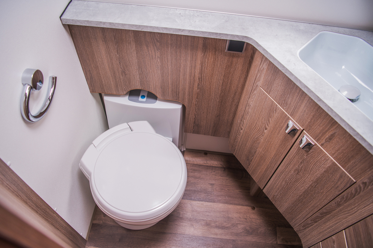 A composting toilet is inside of a small bathroom.