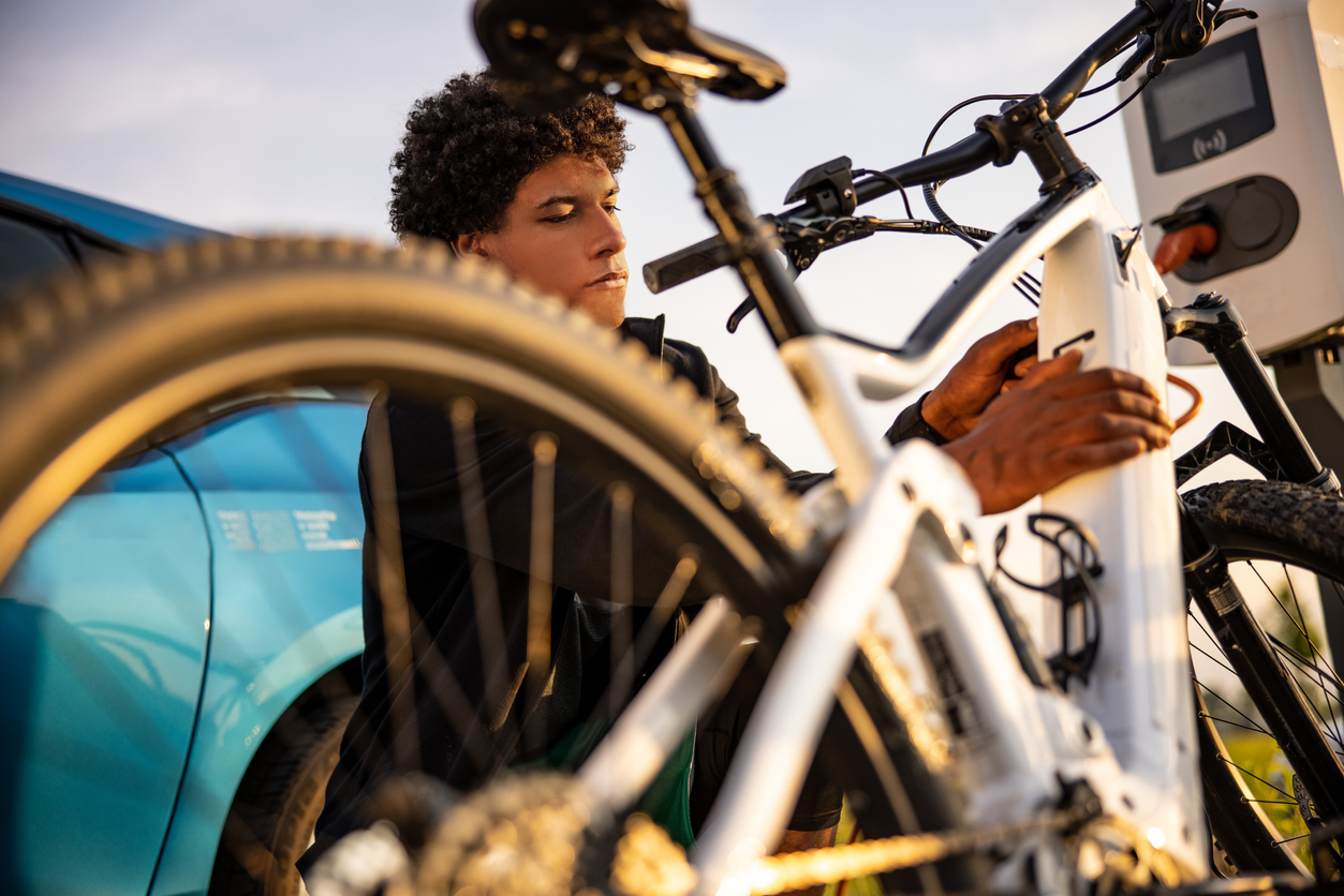 young-person-works-on-the-battery-compartment-of-an-electric-bike-outdoors