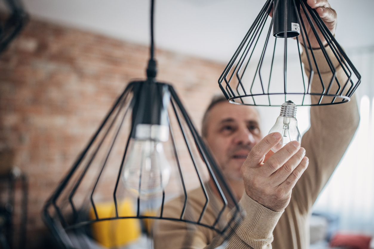 A man changes a light bulb in an apartment by himself