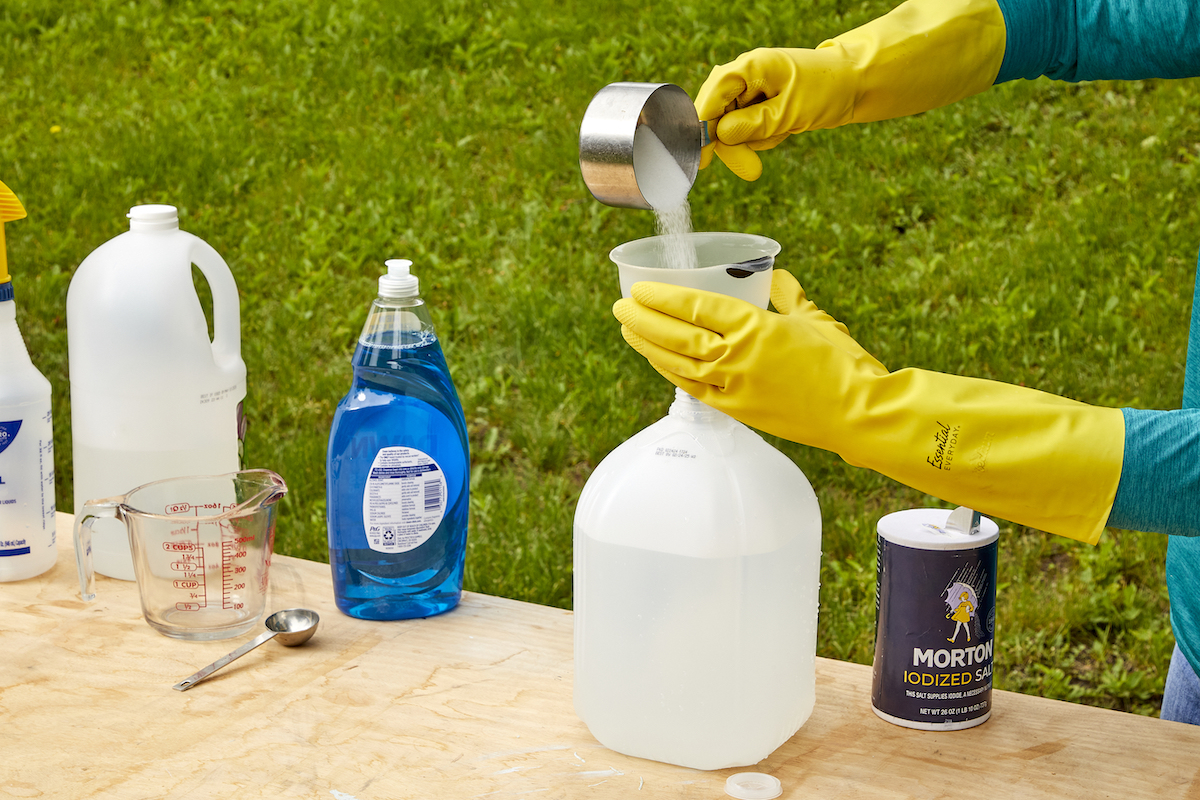 Woman uses funnel to pour salt into a bottle. 