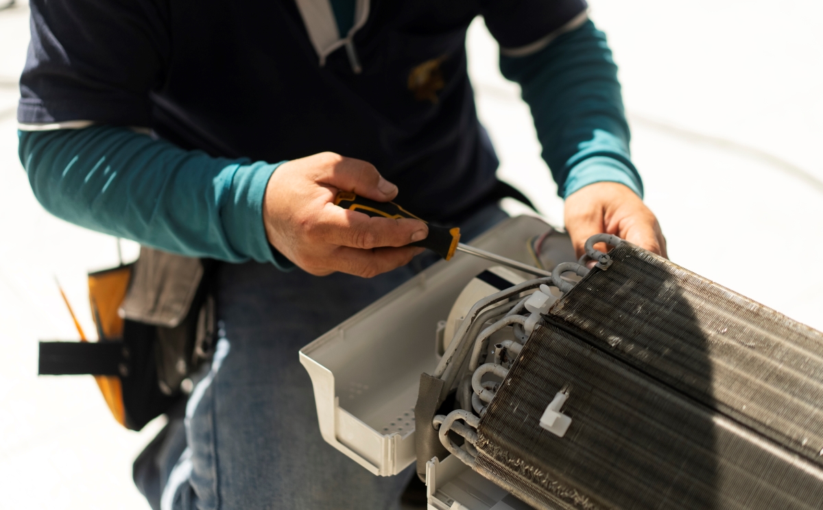 A technician is using screwdriver on heat pump unit coils.