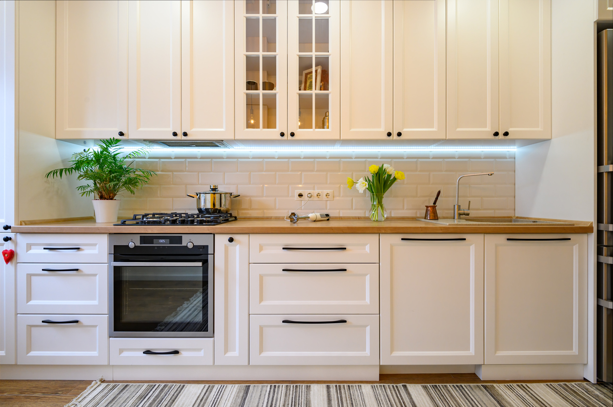 cozy well designed modern kitchen interior with appliances and dining table and under cabinet lighting.