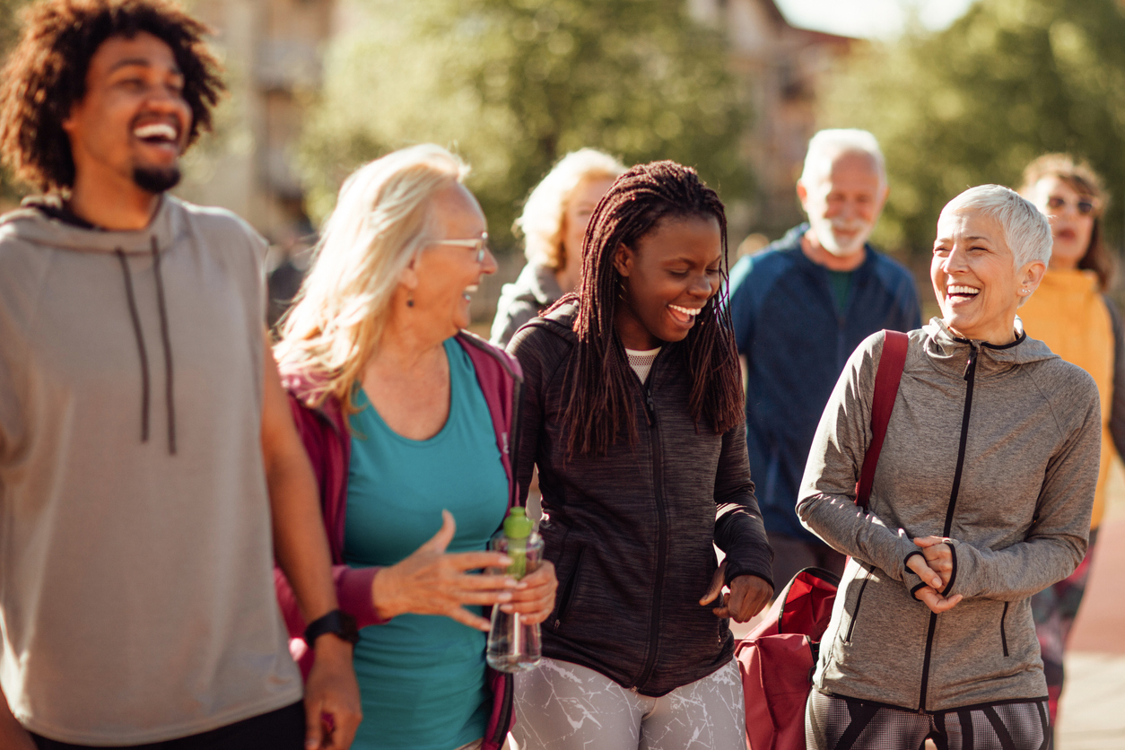 iStock-1153816876 communauté planifiée de grande envergure Groupe de personnes souriantes marchant ensemble en plein air