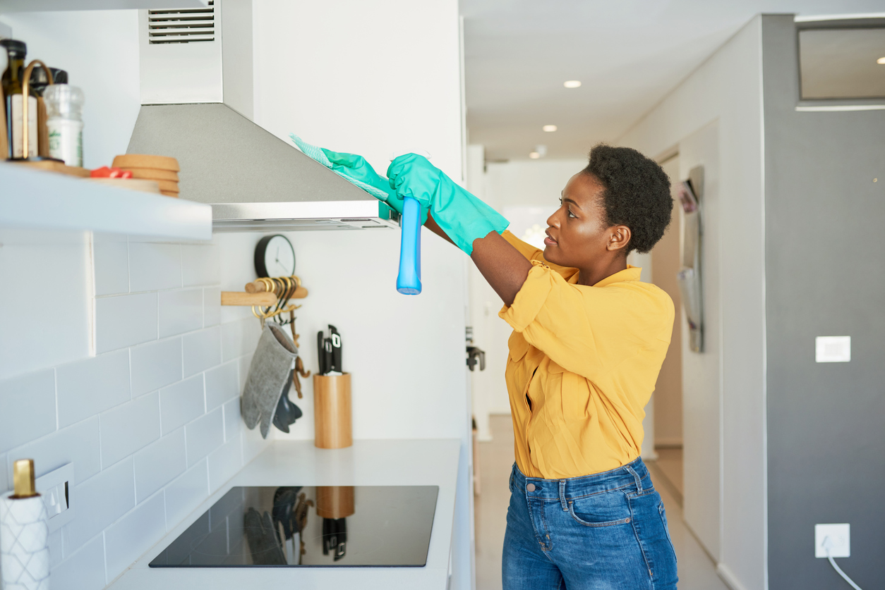 femme-nettoie-une-hotte-de-cuisine-dans-une-cuisine-blanche