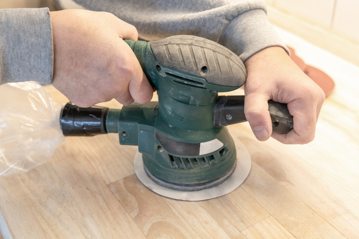 Utilisation d'une ponceuse à bois sur un bloc de boucherie en bois. 