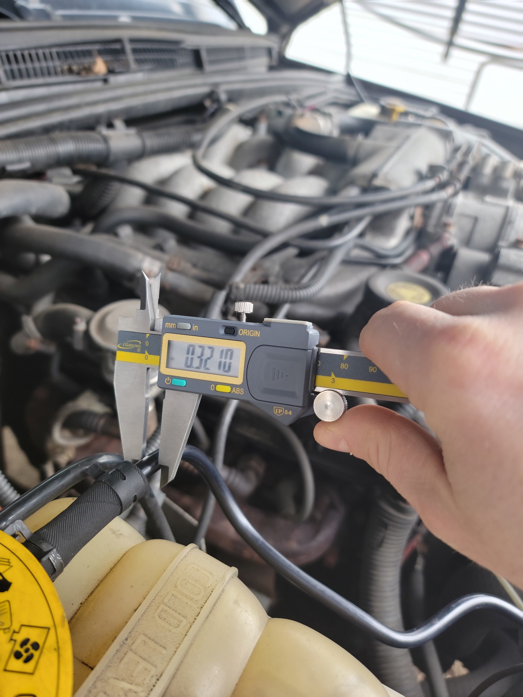 A person using the best digital caliper to check the accuracy of a car's fittings.