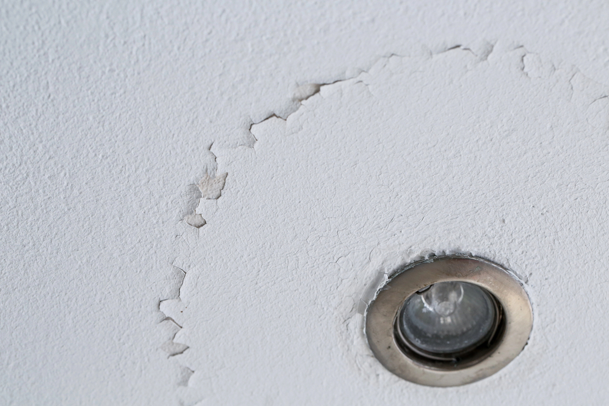 A ceiling light is next to peeling white paint.