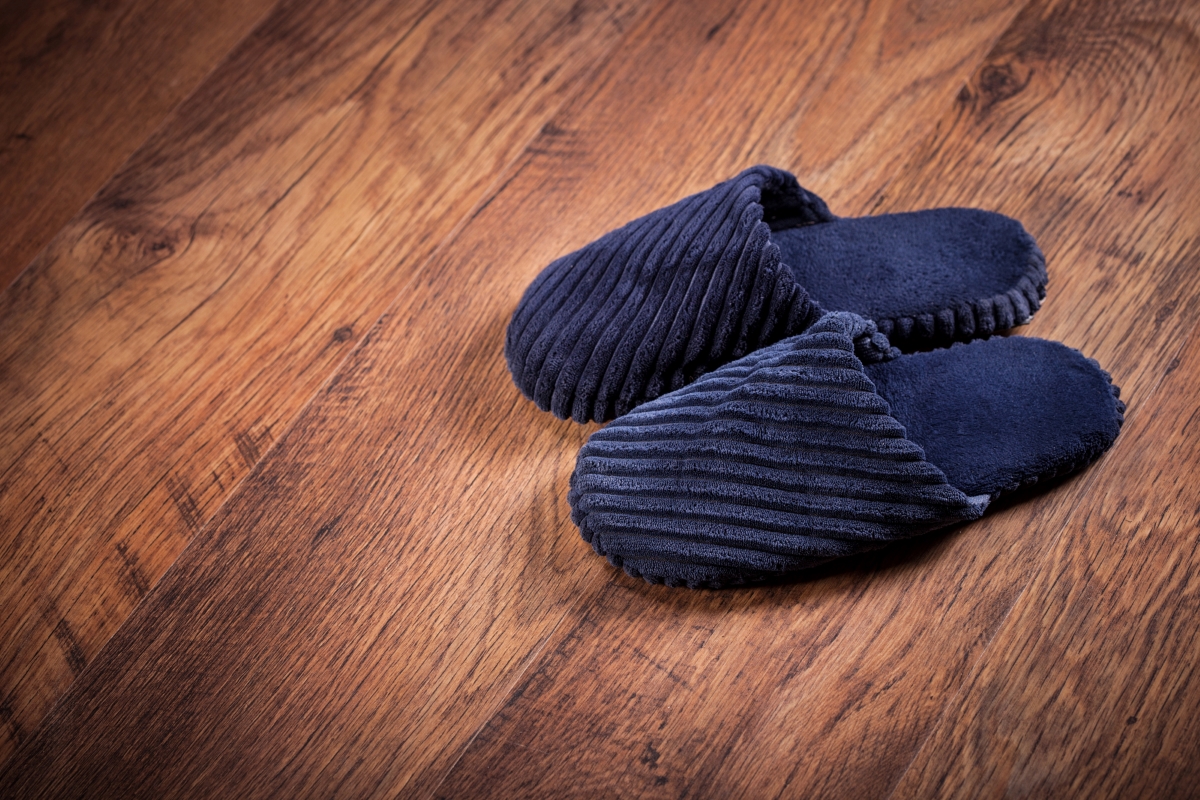 A pair of navy slippers on the dark wooden hard floors.