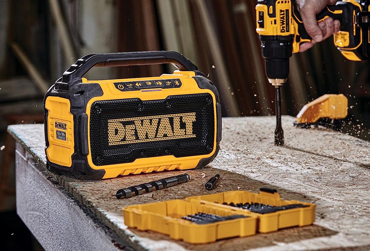 The best DeWalt jobsite radio on a workbench next to a person using the best DeWalt cordless drill