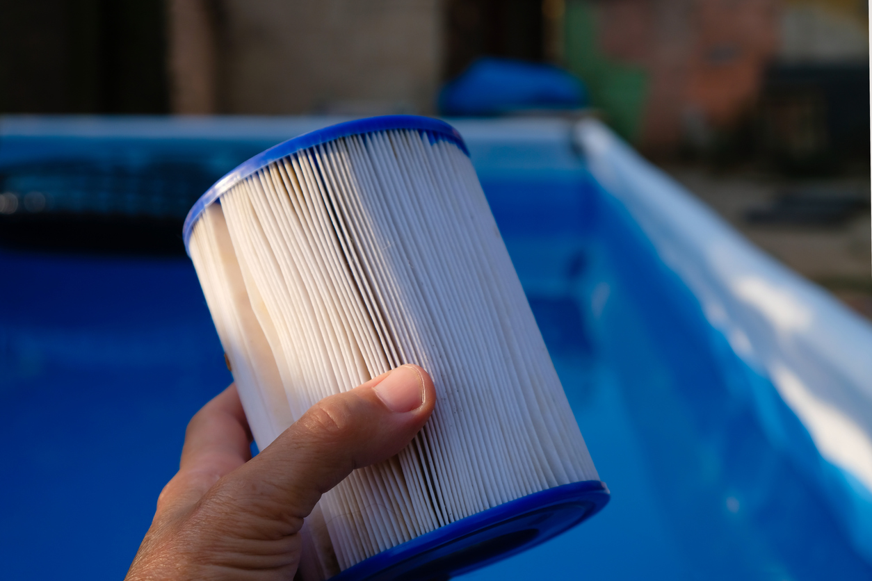 Main tenant une cartouche de filtre de piscine propre au-dessus d'une piscine hors sol