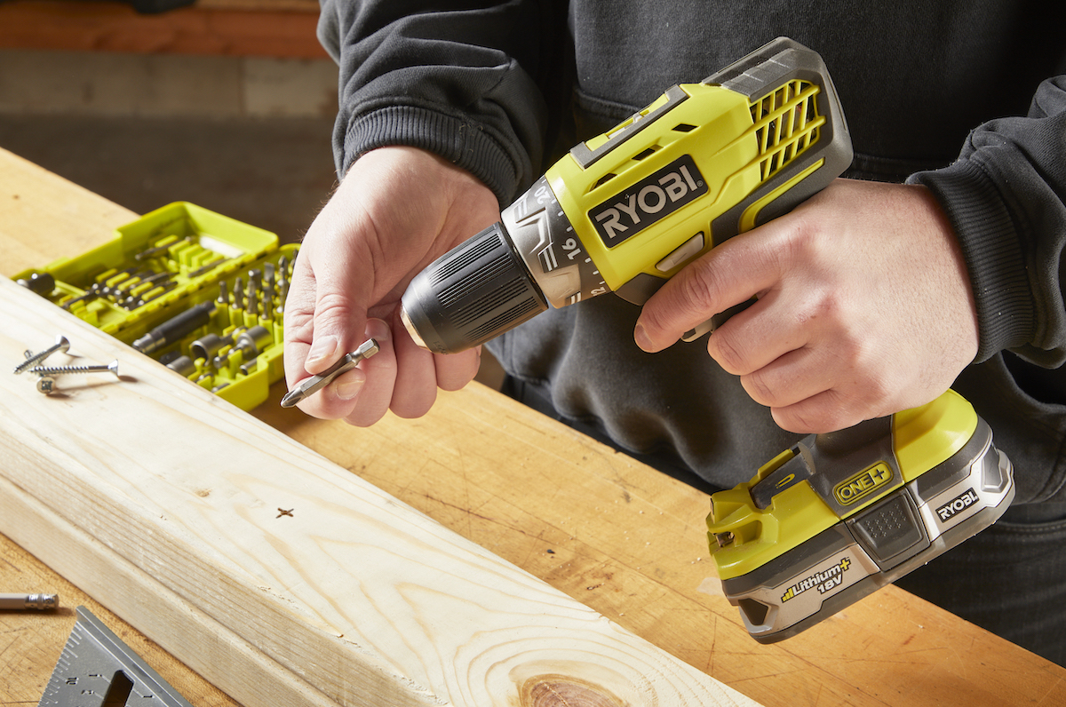 Man fits drill with screwdriver bit.