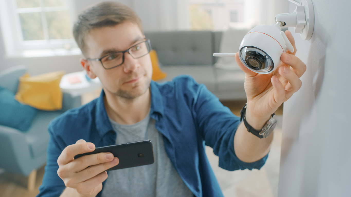 iStock-1212406152 must dos December man checking smart security camera