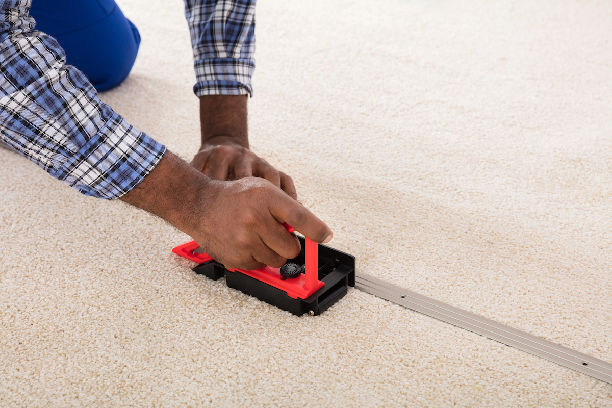 Une personne installe un tapis blanc avec un outil.