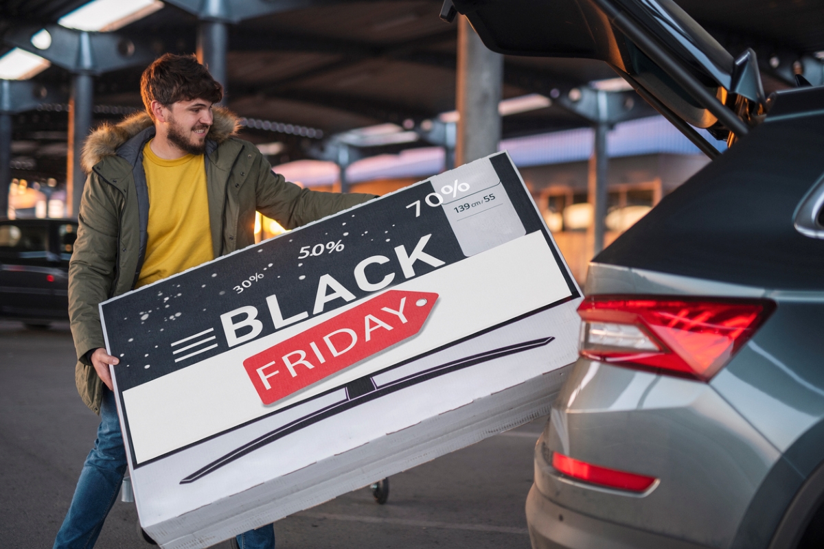 Man putting Black Friday box in car.