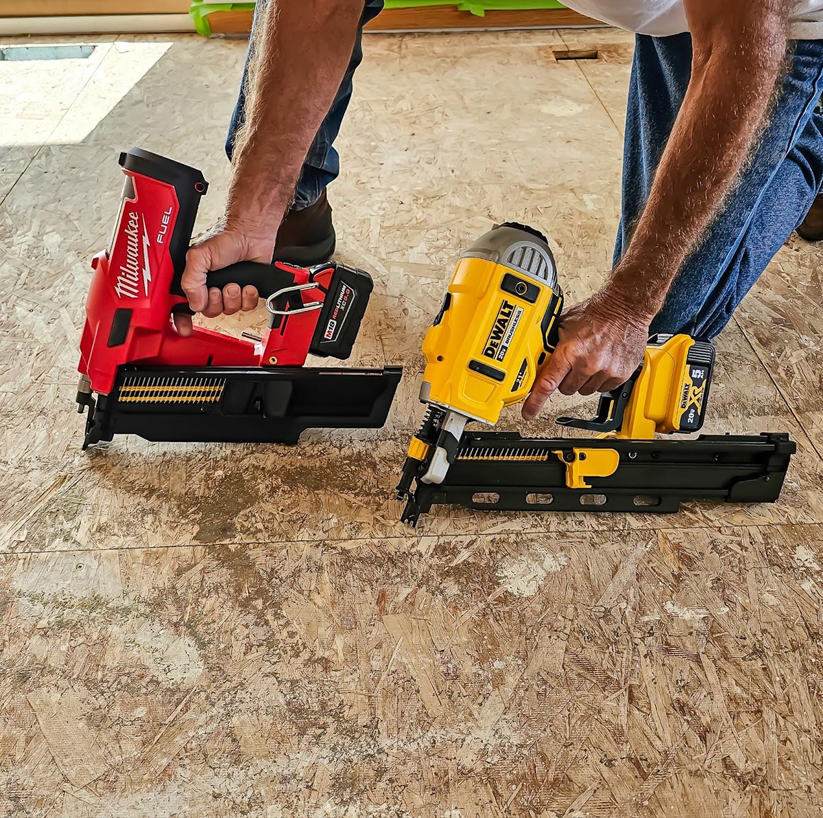 DeWalt Building contractor holding a DeWalt Cordless Framing Nailer and a Milwaukee Cordless Framing Nailer side by side.