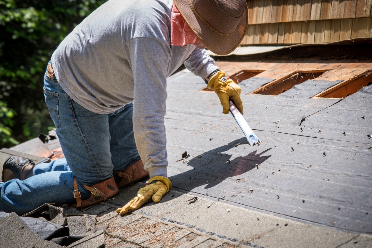 A man is removing shingles from the roof.