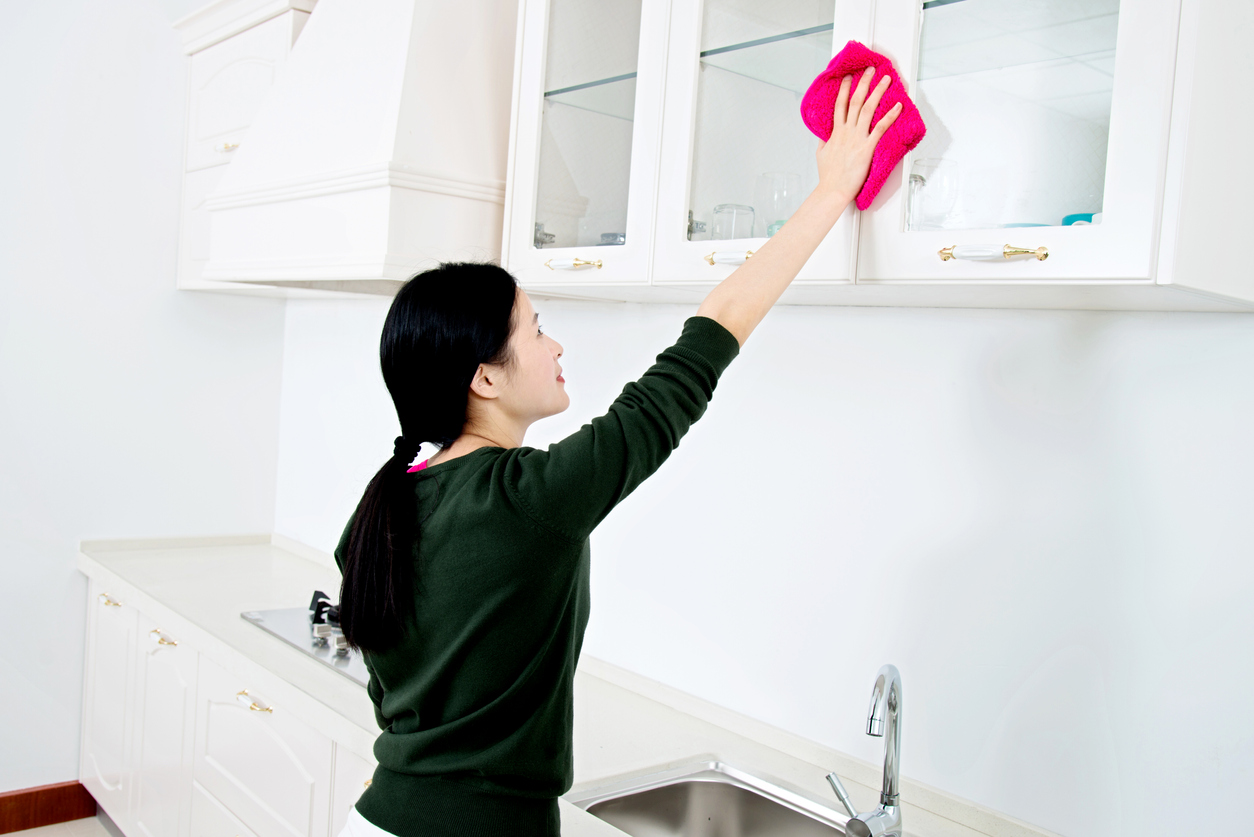 asian woman cleaning kitchen cabinets