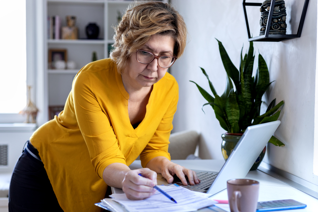 mature woman reviewing applications next to laptop