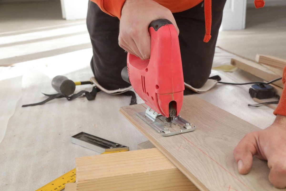 A close up of a worker cutting planks for a flooring project.