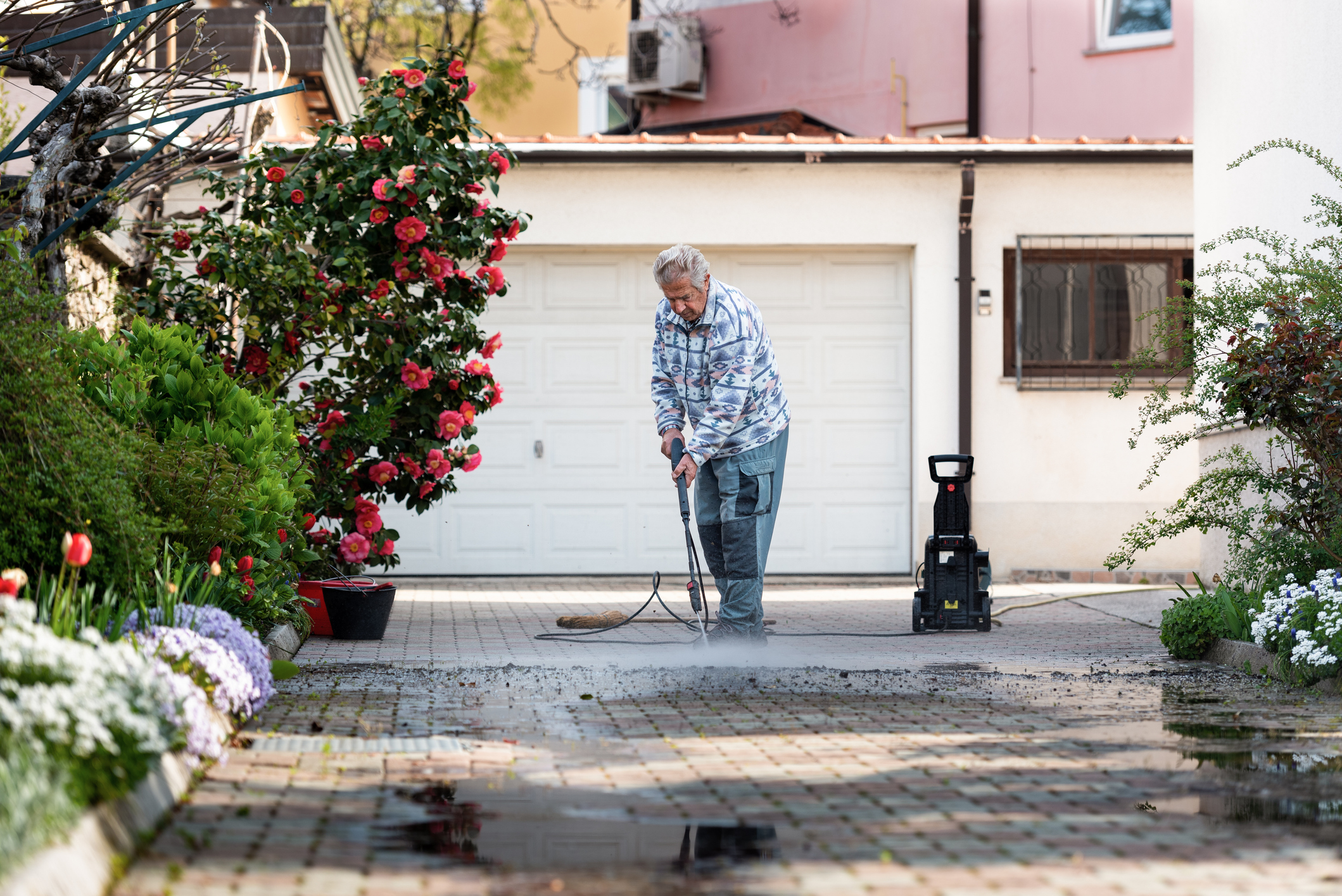 A man cleans his driveway with a high pressure washer