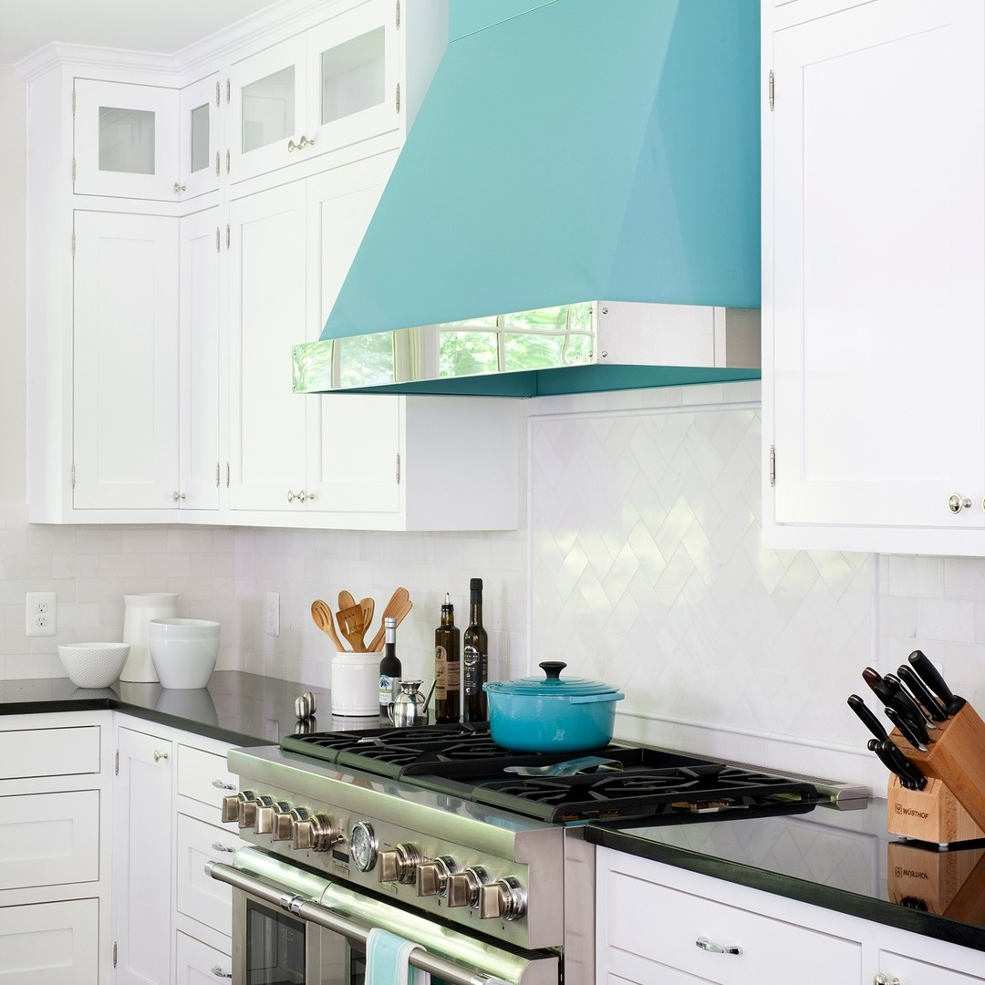 A robin's egg blue range hood with stainless steel trim in a white kitchen and matching pot.