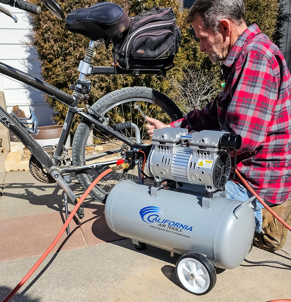 Une personne utilisant le compresseur d’air California Air Tools 8010 pour gonfler les pneus de vélo pendant les tests.