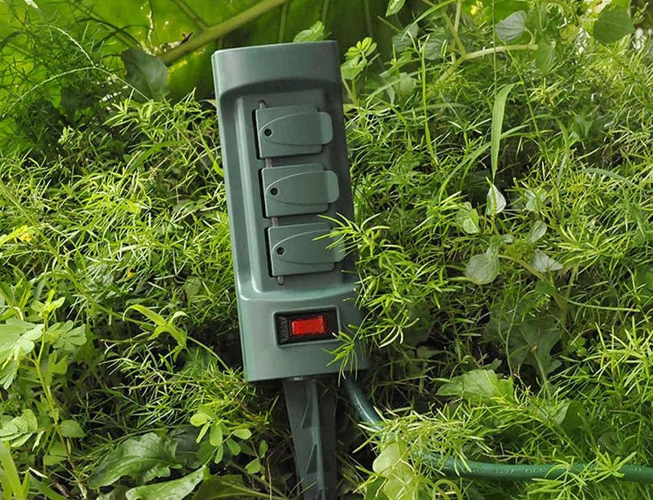 Vue rapprochée d'un piquet d'énergie verte planté dans le feuillage près d'un trottoir.