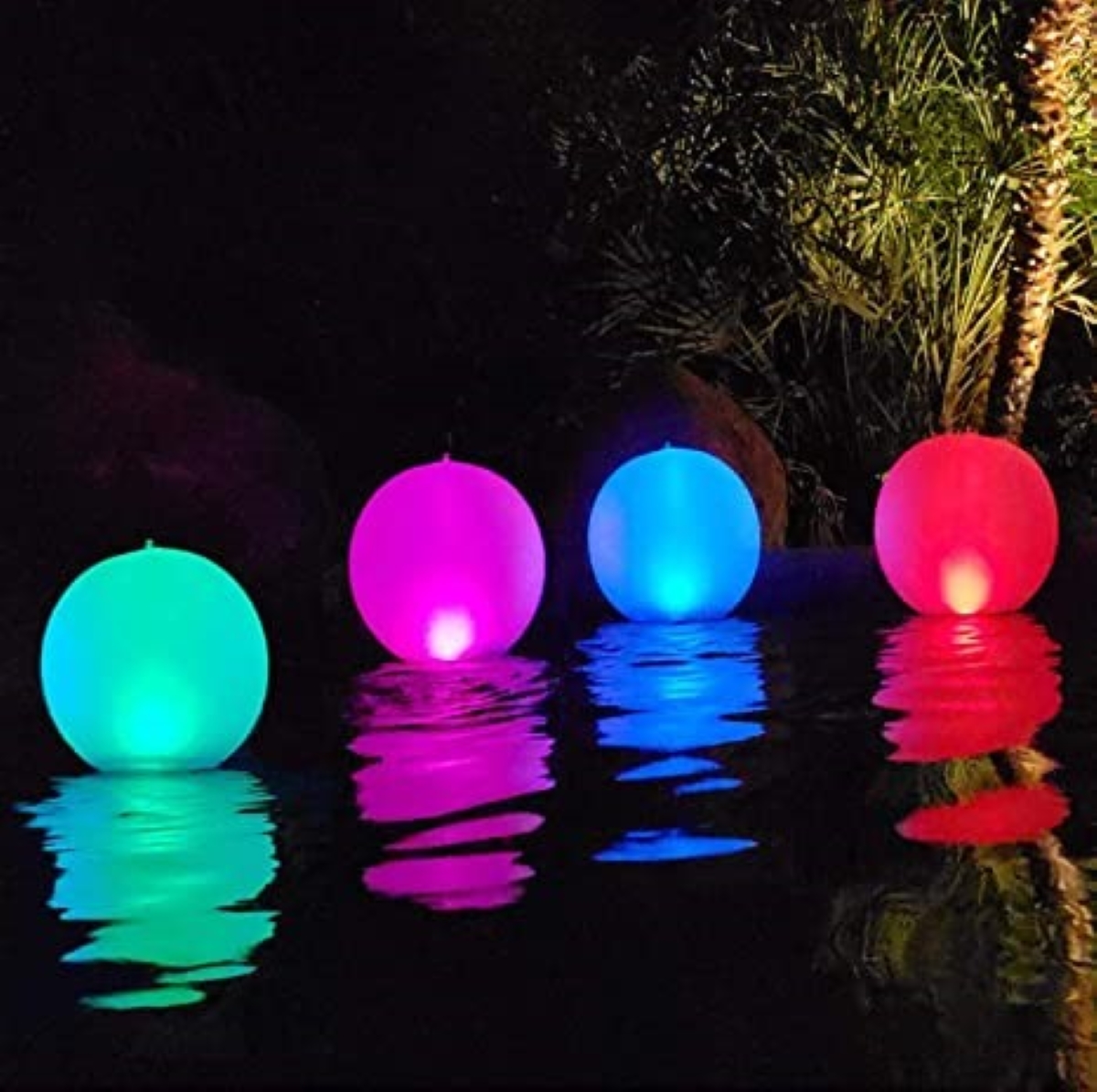 A pool at nighttime lit with multi-colored floating globe lights.