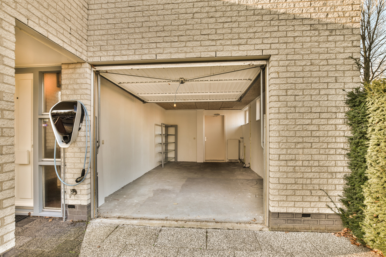 Tan brick home with clean garage with door open.