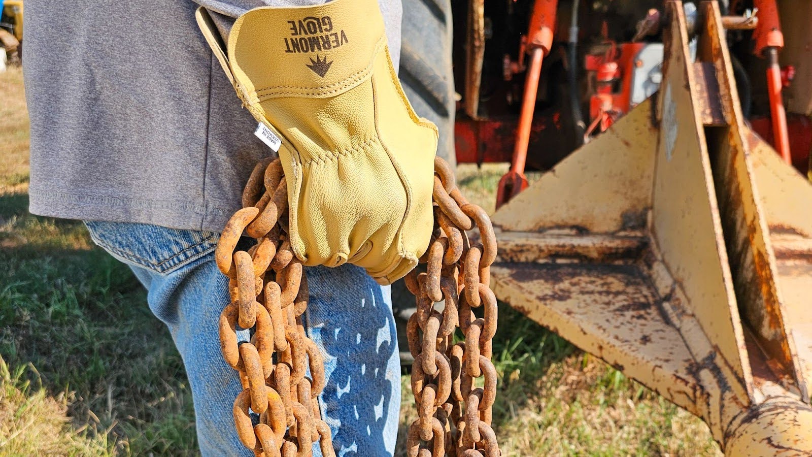 Person wearing yellow Vermont goatskin work gloves holding a rusty chain