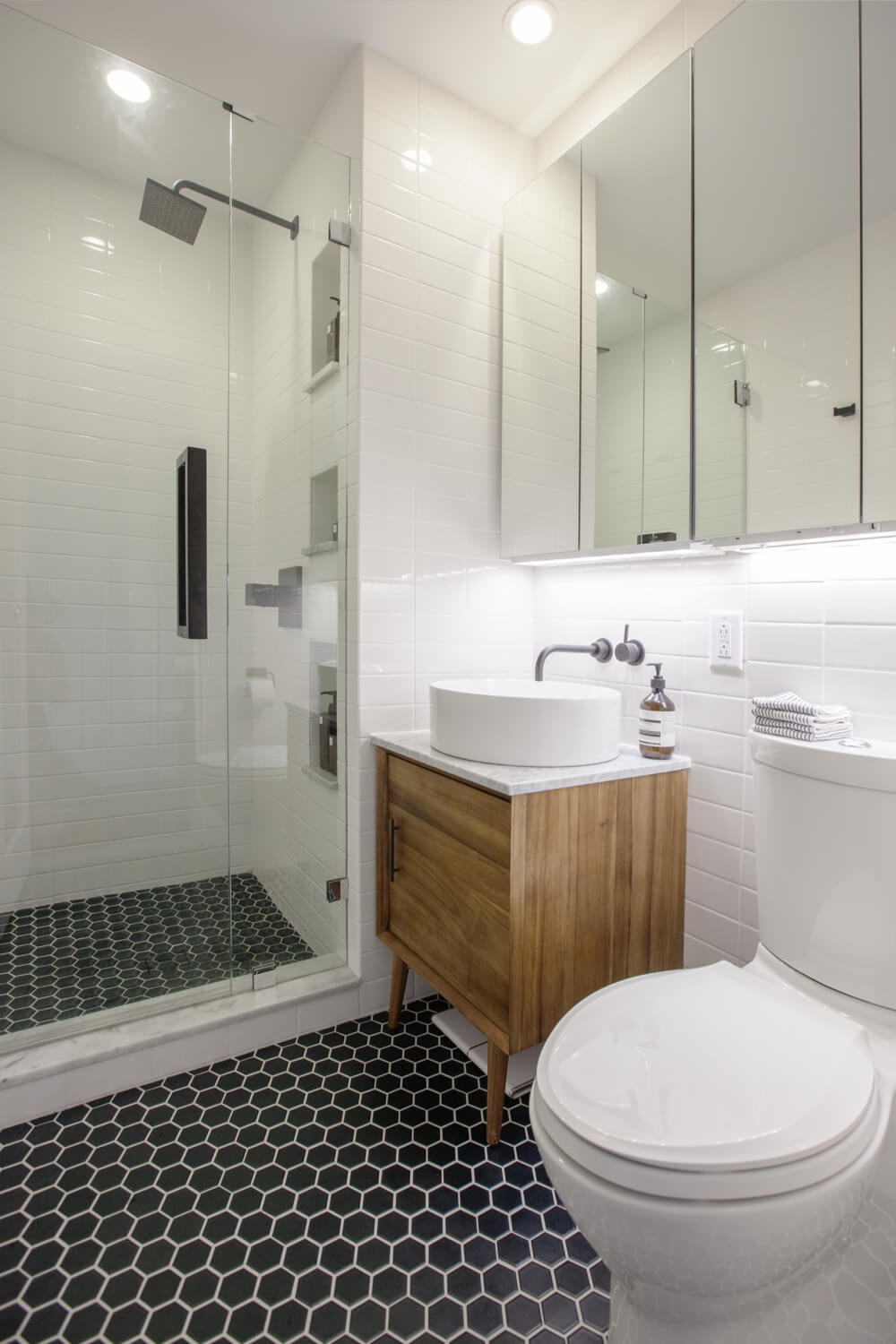 A bathroom with a light wood vanity and mirrored IKEA medicine cabinets.