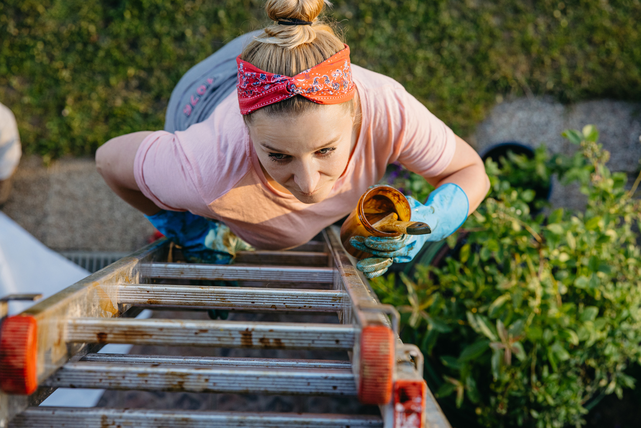 iStock-1359667480 productivity hacks woman climbing ladder to paint